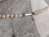 necklace with pearls and a charm on a mannequin base