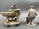 three figurines of men sitting on a bench