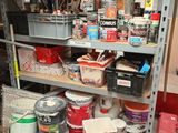 a shelf full of paint and other items in a room