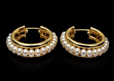 a pair of pearl hoop earrings on a black background