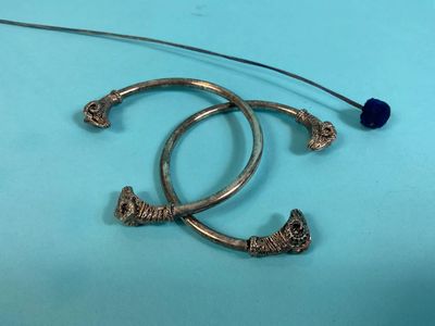 a close up of a pair of silver hoop earrings on a blue surface