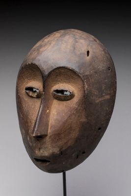 une image représentant un masque en bois posé sur un socle, sur fond gris