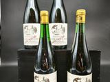 quatre bouteilles de vin sont posées dans une caisse en bois sur une table