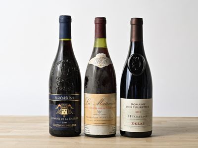 trois bouteilles de vin sont alignées sur une table en bois