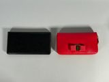 two pieces of red and black purses on a white table