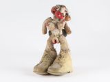 une petite statue représentant un clown assis sur une paire de chaussures