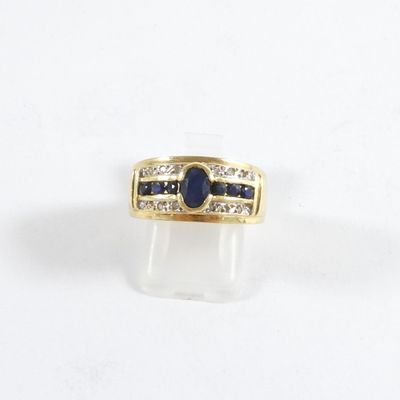 gros plan d'une bague en or avec une pierre bleue et des diamants