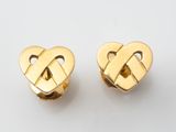 une paire de boucles d'oreilles en or en forme de cœur posées sur une surface blanche
