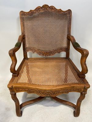 une chaise en bois avec une assise en osier et des accoudoirs