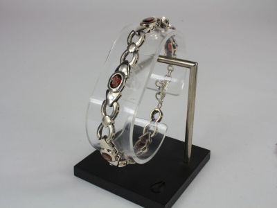 silver bracelet with garnett on display on a black stand