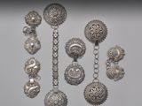 Plusieurs bijoux en argent sont exposés sur une surface blanche