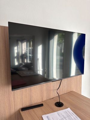 a flat screen tv sitting on a desk in front of a window