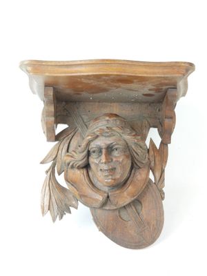 a wooden shelf with a carved head on it