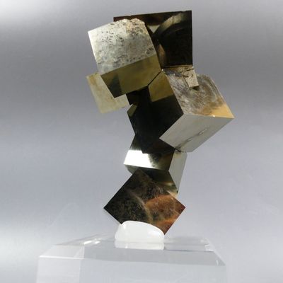 sculpture made of metal blocks on a clear base on a gray background