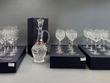 four wine glasses and a decanter in a box on a table