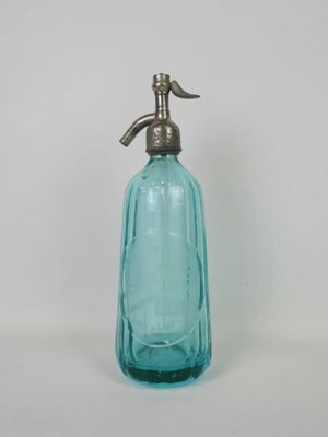 a blue glass bottle with a metal handle on a white surface