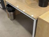 a desk with a glass top in the middle of a room