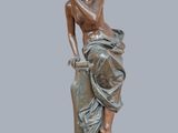 bronze statue of a woman sitting on a rock with her hand on her chin