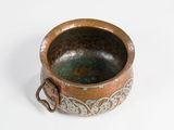 a small metal bowl with a handle on a white surface