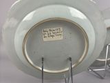 a white plate with a gold rim sitting on a metal stand