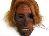 un masque à l'aspect effrayant, avec de longs cheveux, posé sur un fond blanc