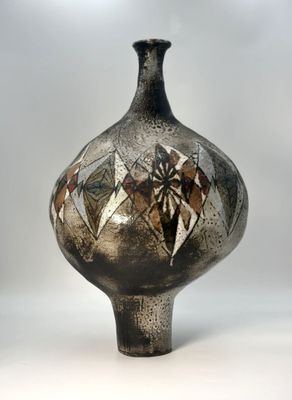 a black vase with a design on it sitting on a white surface