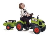 une petite fille assise sur un tracteur jouet