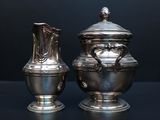 two silver vases sitting next to each other on a table