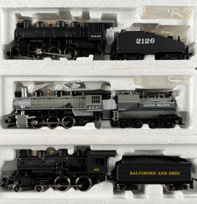 three train engines in a display case on a table