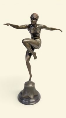 statue en bronze représentant une femme assise sur un rocher, les bras tendus