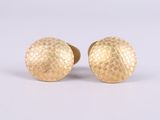 a pair of gold earrings with a textured surface