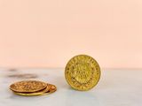 two gold coins sitting on top of a table next to each other