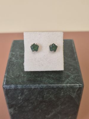 a pair of green earrings sitting on top of a marble block