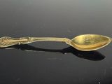 a gold spoon with a spoon handle on a black surface