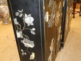 a black cabinet with white flowers on it in a room