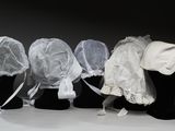 quatre têtes de mannequins, coiffées de voiles et de chapeaux, alignées les unes à côté des autres