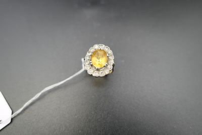 une image montrant un gros plan d'une bague sertie d'un diamant jaune et blanc posée sur une surface noire