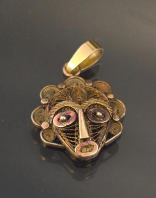 a close up of a gold pendant with a face on it