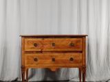 une commode en bois posée contre un rideau blanc