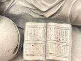 a statue of a woman holding a book and a ball