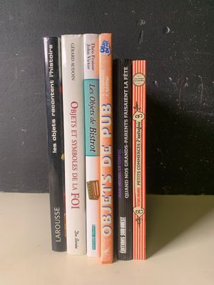Plusieurs livres sont empilés les uns sur les autres devant un mur noir.