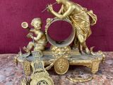une statue représentant une femme et deux enfants jouant avec une horloge