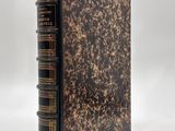 an old book with a brown cover sitting on top of a white surface