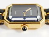 a gold watch with a black face on a white surface