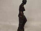 a bronze statue of a woman with her hands on her chest