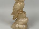 a small statue of an owl sitting on top of a rock