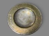 a silver plate with a hole in it on a gray surface