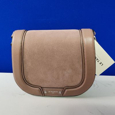 a tan leather purse on a white table with a blue background