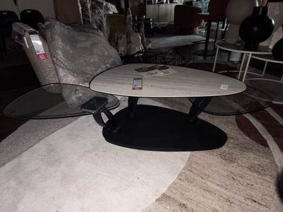 une table en marbre blanc avec un piètement noir et un plateau en verre