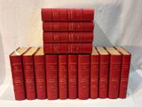 six livres rouges empilés les uns sur les autres sur une surface blanche
